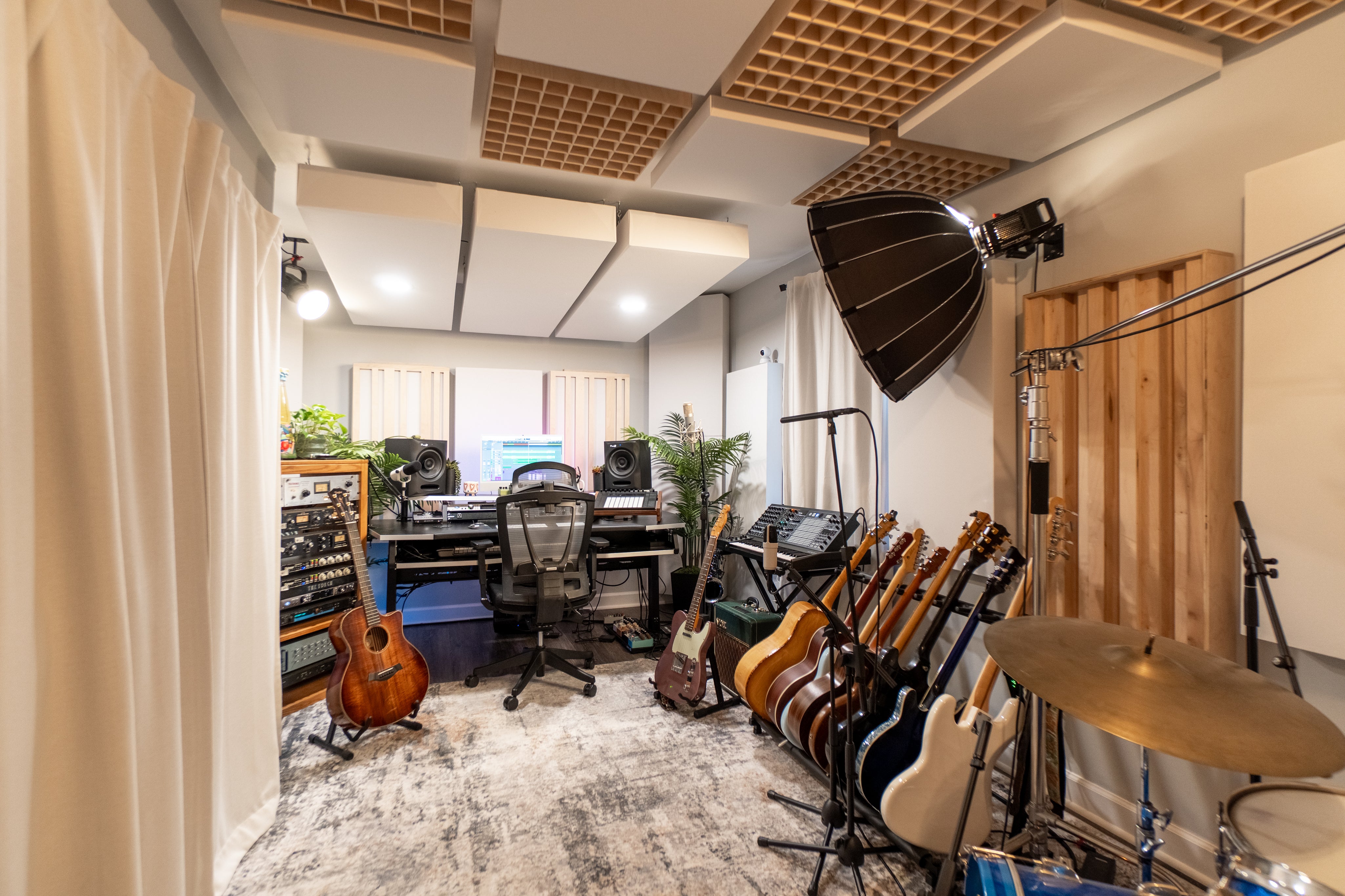 Music studio with guitars, a drum set, and recording equipment.