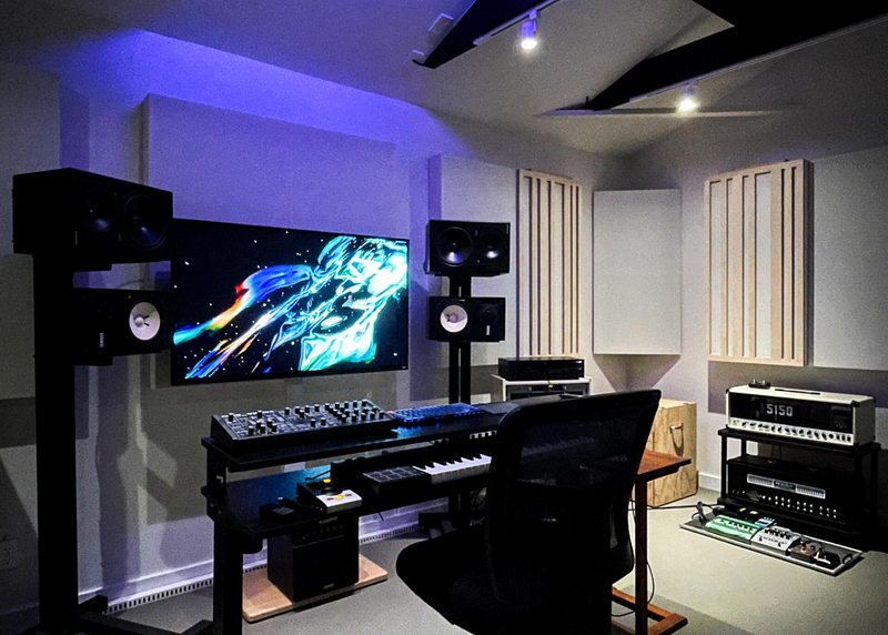 Modern home studio with audio equipment and a large screen displaying colorful graphics.